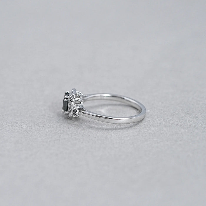 side view of asscher cut black diamond halo engagement ring on grey background