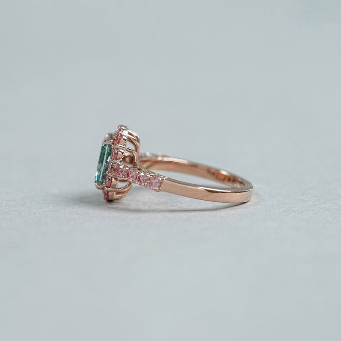 side view of green radiant cut diamond with pink diamond halo engagement ring