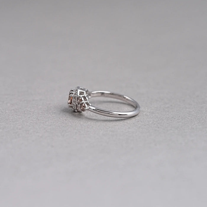 left side view of brown cushion cut diamond halo wedding ring on grey fabric