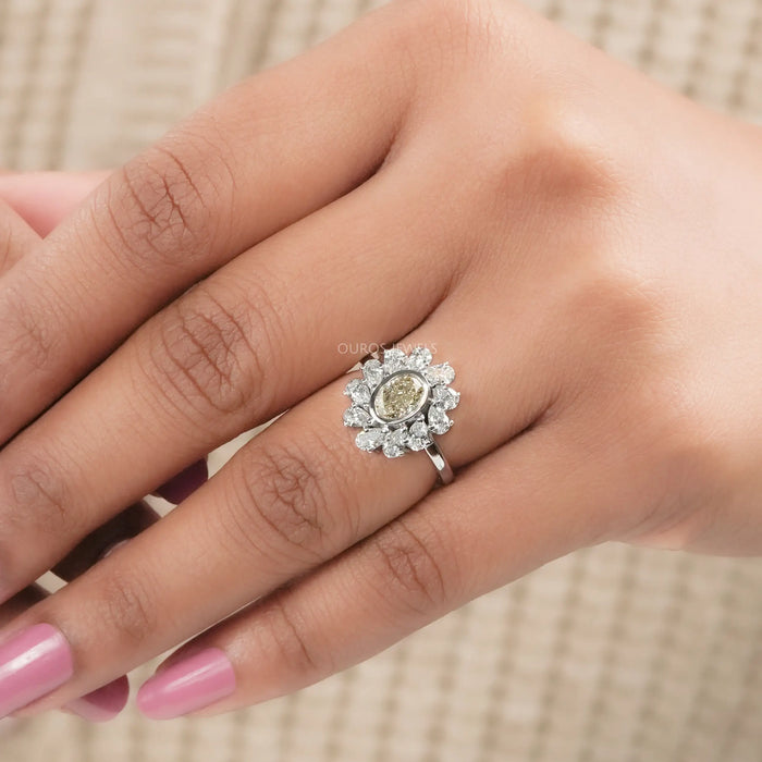 yellow oval cut diamond bezel set with pear halo engagement ring on model's finger