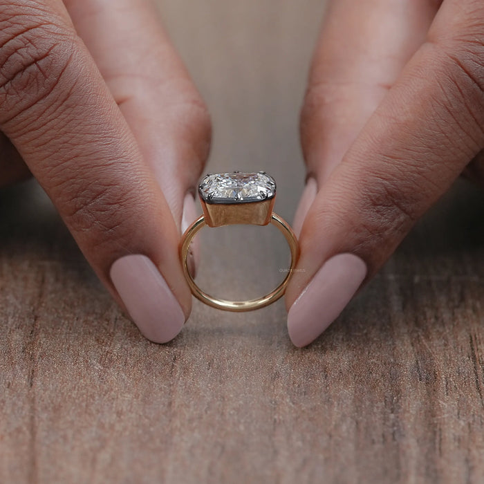 close up view of east west cushion diamond solitaire ring with black coated band