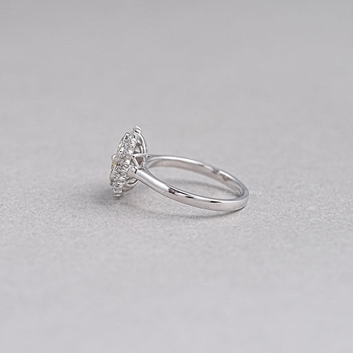 side view of yellow pear diamond floral halo engagement ring on grey fabric