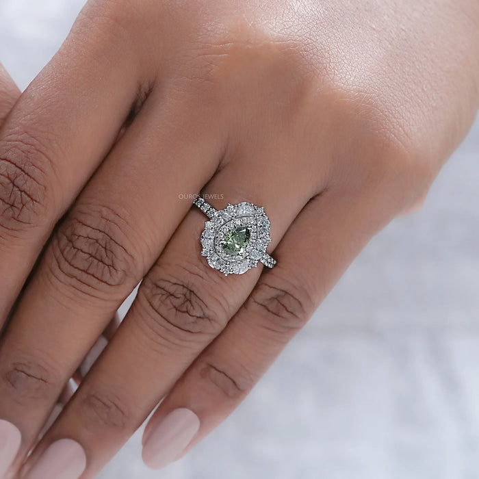 green pear cut surround double halo diamond engagement ring on model's finger