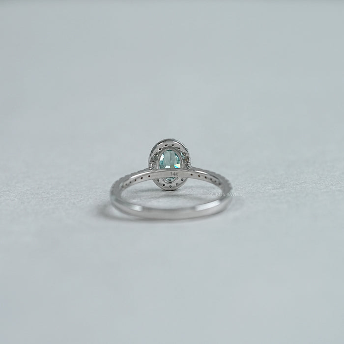 back view of fancy vivid green oval cut diamond halo wedding ring on grey fabric