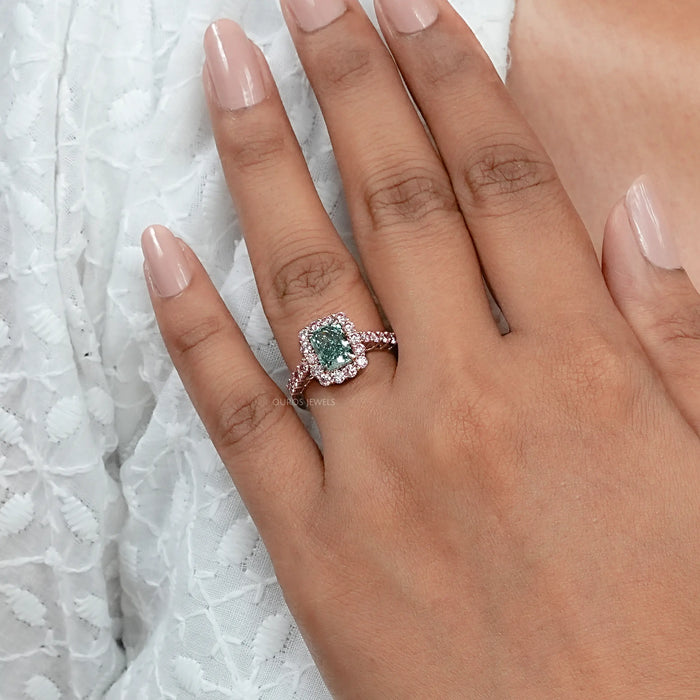green radiant cut diamond with pink diamond halo engagement ring on model's finger