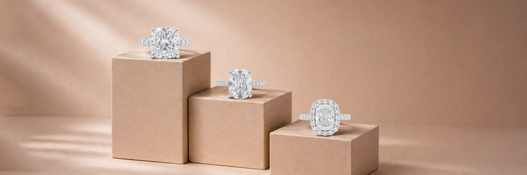 Cushion cut lab-grown diamond engagement rings in white gold — large cushion solitaire with pavé band, elongated cushion solitaire with thin pavé band, and cushion cut diamond halo with pavé band on beige pedestals