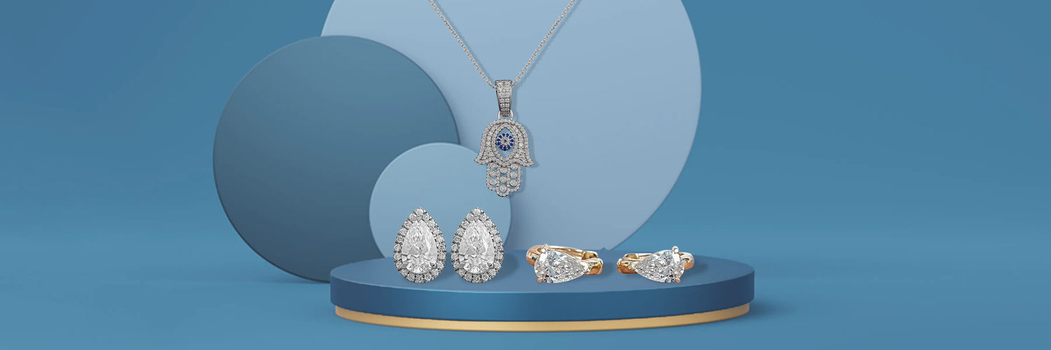 Lab-grown diamond fine jewelry set in yellow gold — pear cut solitaire pendant necklace on dark green pedestal, round brilliant four-prong stud earrings, and round brilliant tennis bracelet with pear cut clasp accent on dark marble surface