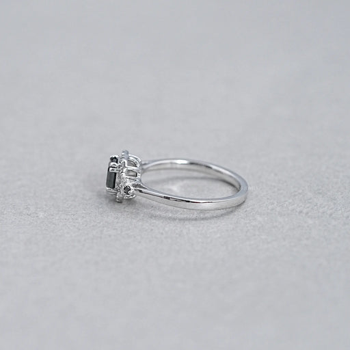 side view of asscher cut black diamond halo engagement ring on grey background