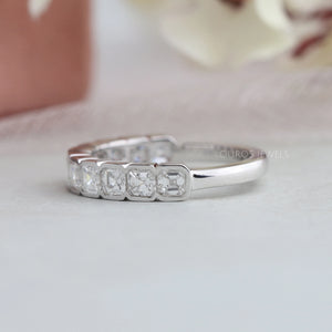 Asscher Cut Lab Diamond Half Eternity Wedding Band is displayed on a soft surface with a blurred floral background.