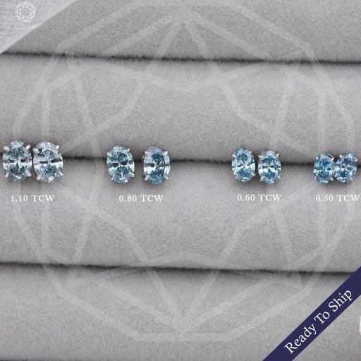 front view of blue oval cut lab grown diamond studs earrings white gold on box