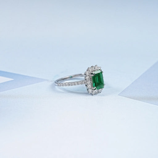 green emerald gemstone with round diamond halo wedding ring's side view