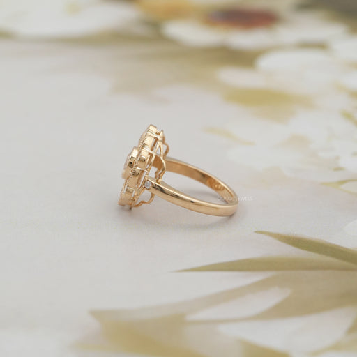 side view of old cut round diamond flower halo engagement ring on grey fabric