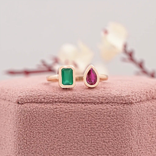 rose gold bezel green emerald and red pear gemstone open wedding ring on jewelry box