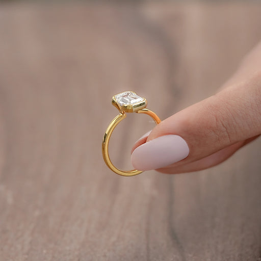 side angle view of emerald cut diamond bezel set solitaire engagement ring