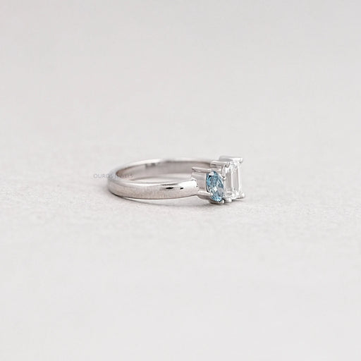 side view of two-stone emerald-cut diamond toi et moi wedding ring on grey fabric