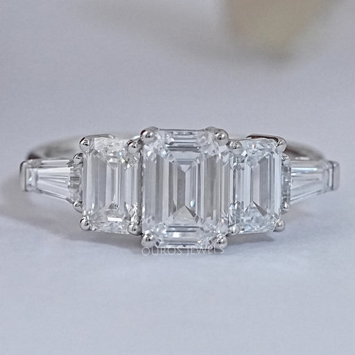 front view of emerald cut lab diamond five stone engagement ring on grey fabric