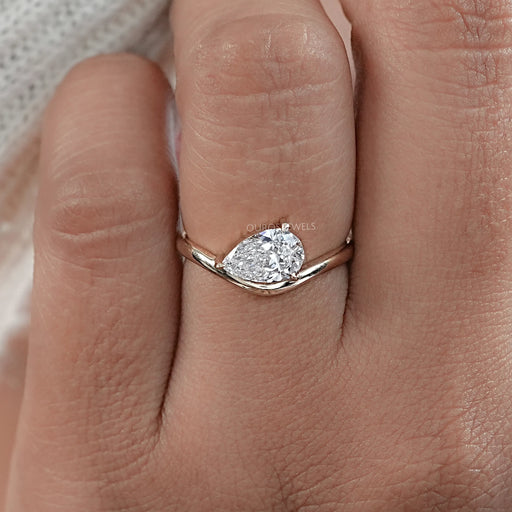 front view of pear cut lab diamond curved engagement ring in finger