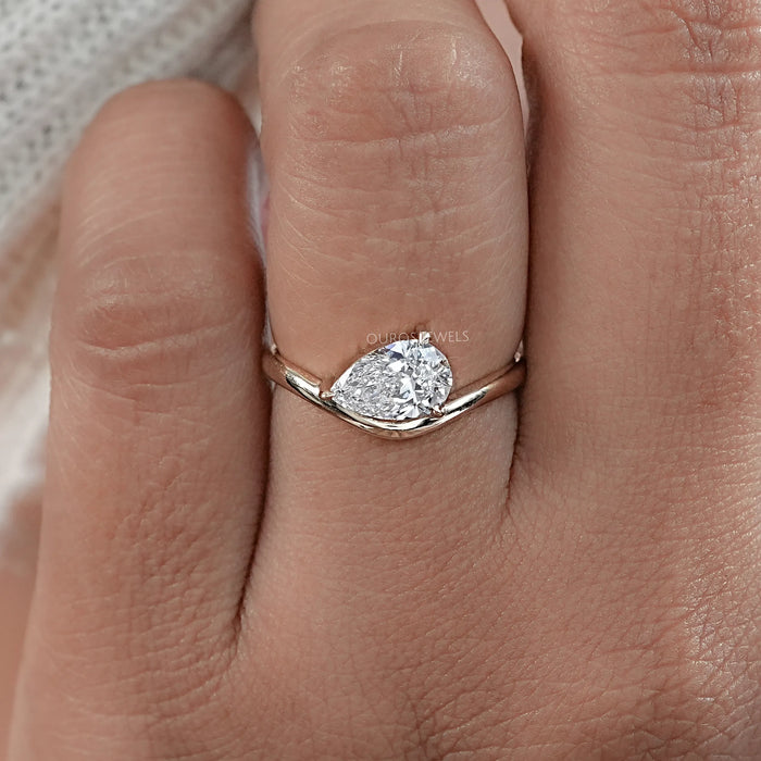 front view of pear cut lab diamond curved engagement ring in finger