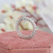 Round Cut Lab Diamond Eternity Wedding Band displayed on a pink cushion, highlighting the intricate design and sparkling diamonds with a blurred floral background.