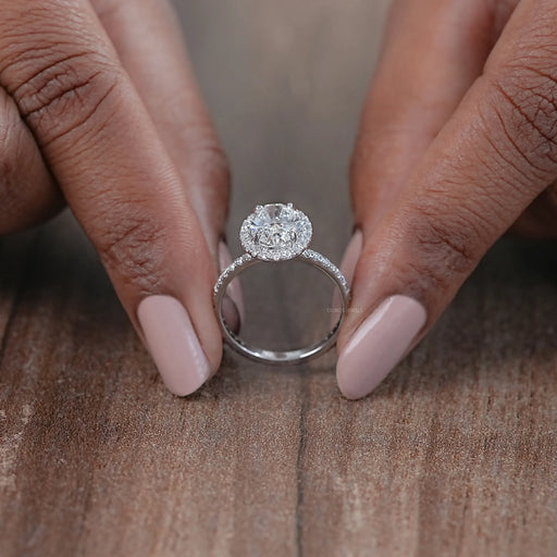 close view of oval cut lab diamond halo engagement ring on brown background