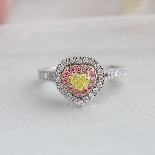 top view of yellow heart shaped diamond double halo engagement ring on grey fabric