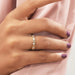 Round Cut Lab Diamond Eternity Wedding Band worn on a hand with light purple nail polish against a soft pink fabric background, showcasing alternating round and baguette-cut lab-created diamonds.