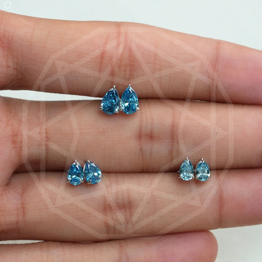 top view of blue pear cut man made diamond stud earrings white gold on finger