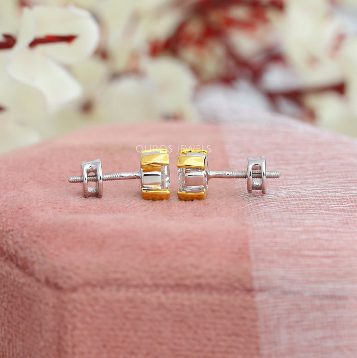 Asscher Cut Diamond Two Tone Stud Earrings, showcasing a side view with a secure screw back design, highlighting the intricate yellow and white gold settings on a soft pink background.