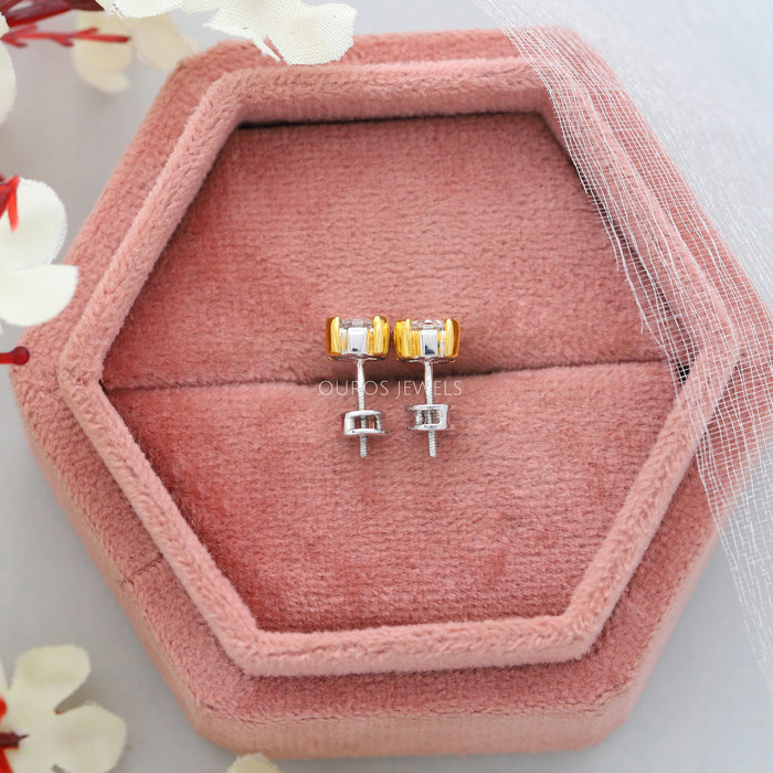 Asscher Cut Diamond Two Tone Stud Earrings, elegantly displayed in a hexagonal pink jewelry box, featuring yellow and white gold settings with secure screw backs.