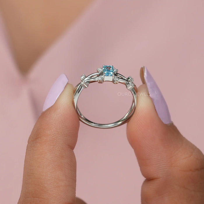 Infinity style diamond wedding ring with blue colored radiant diamond