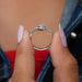 Two finger front view of heart cut diamond ring, main center stone colorless with VS clarity.