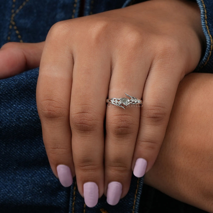 Finger front view of olive pear diamond ring set in bypass. Crafted with 14k white gold.