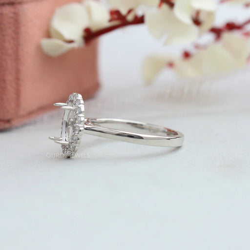 side view of oval-shaped halo semi-mount engagement ring on grey fabric