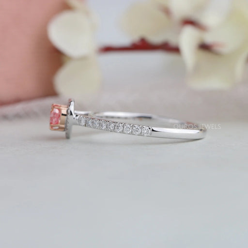 side view of pink heart cut diamond halo engagement ring on grey fabric