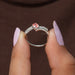 Two finger front view of oval cut diamond engagement ring set in bypass.